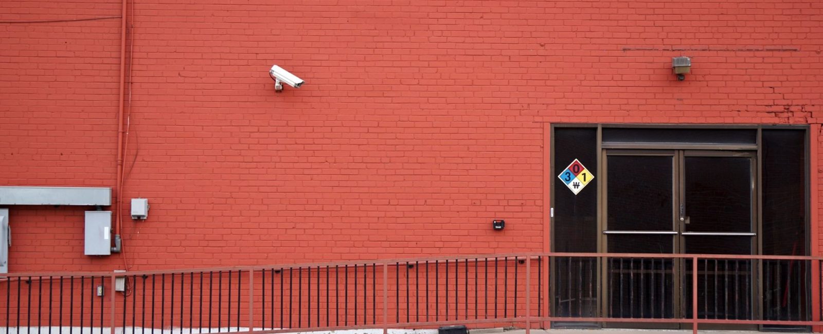 Security camera and rear entrance on a commercial building: Roughly One in Three UK Business Premises Will Suffer Crime This Year