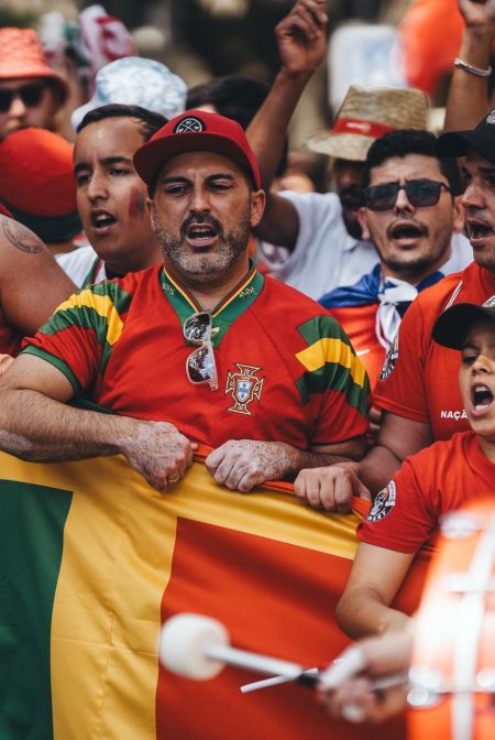 National team supporters in red shirts singing behind a flag