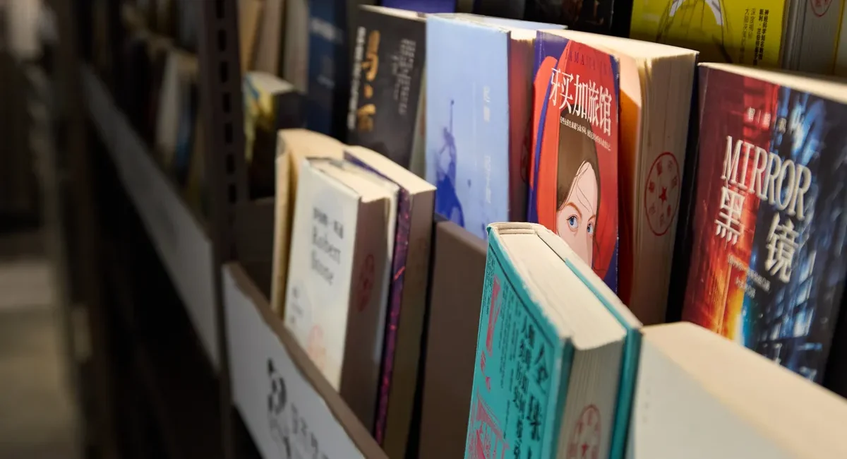 Books neatly arranged on a library shelf, showcasing a variety of genres and languages