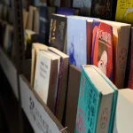 Books neatly arranged on a library shelf, showcasing a variety of genres and languages