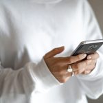 A calmer approach to money: budget first, then plan every repayment: a person in a white jumper checking their household budget on a mobile phone