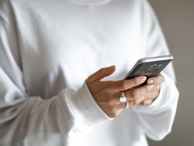 A calmer approach to money: budget first, then plan every repayment: a person in a white jumper checking their household budget on a mobile phone