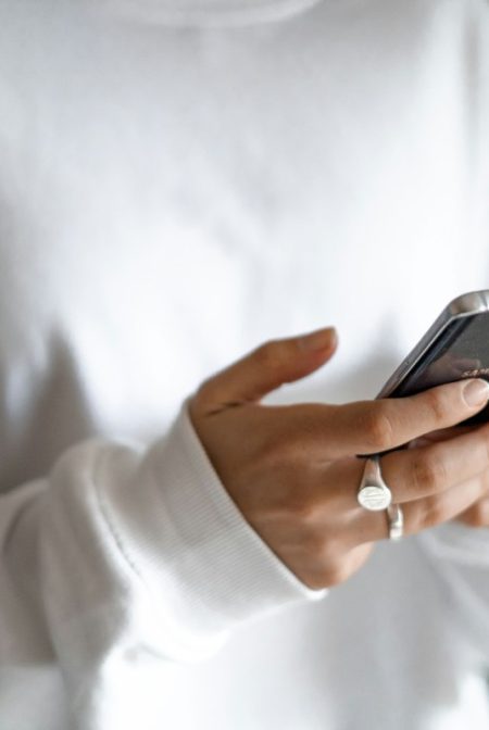 A calmer approach to money: budget first, then plan every repayment: a person in a white jumper checking their household budget on a mobile phone