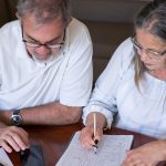 Pension cash taken too soon can create problems you did not expect: an older couple going through pension and retirement paperwork together at home