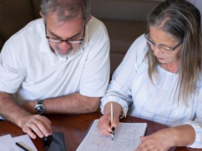 Pension cash taken too soon can create problems you did not expect: an older couple going through pension and retirement paperwork together at home